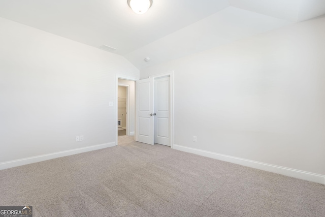 unfurnished bedroom with light carpet, baseboards, and lofted ceiling