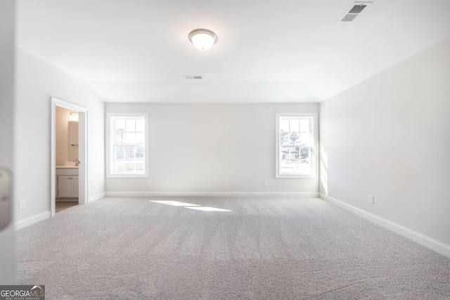 unfurnished bedroom featuring multiple windows, visible vents, and carpet flooring