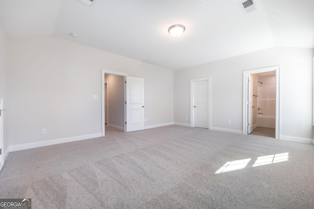 unfurnished bedroom with baseboards, visible vents, vaulted ceiling, and light colored carpet