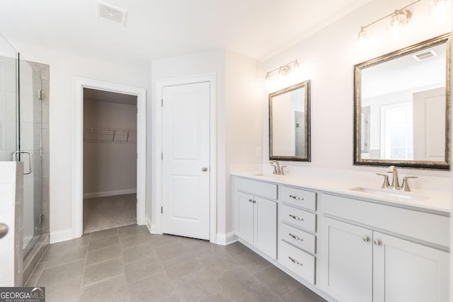 bathroom featuring visible vents, a sink, a shower stall, and double vanity