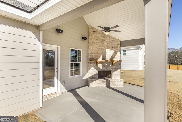 view of patio / terrace featuring an outdoor brick fireplace, fence, and a ceiling fan