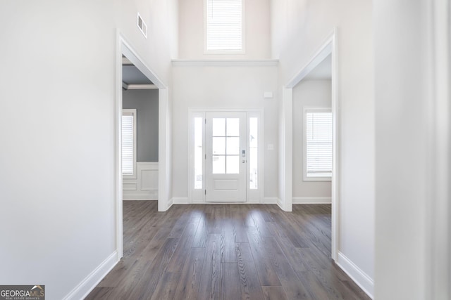 foyer entrance featuring dark wood-style floors, baseboards, and a high ceiling