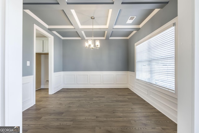 empty room with a notable chandelier, coffered ceiling, visible vents, beam ceiling, and dark wood-style floors