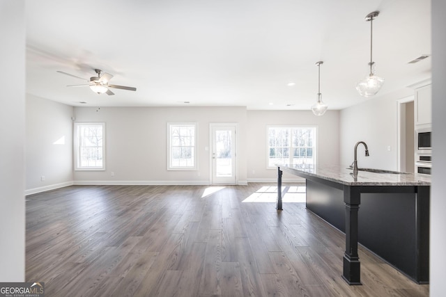 kitchen featuring light stone counters, dark wood-style flooring, visible vents, wall oven, and a sink