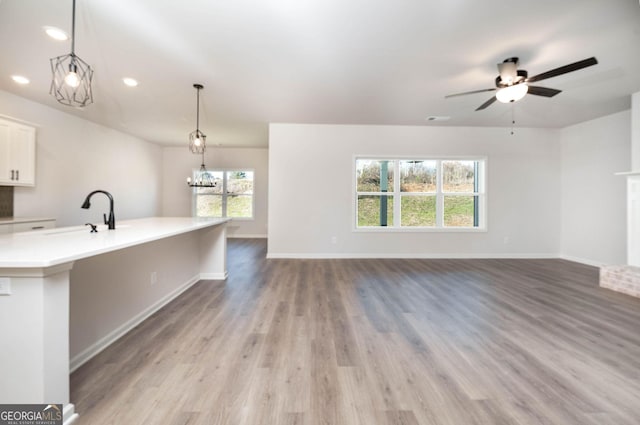 interior space featuring a fireplace, ceiling fan with notable chandelier, light hardwood / wood-style floors, and sink