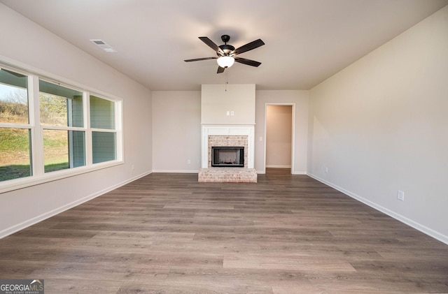 unfurnished living room with ceiling fan, a fireplace, and dark wood-type flooring