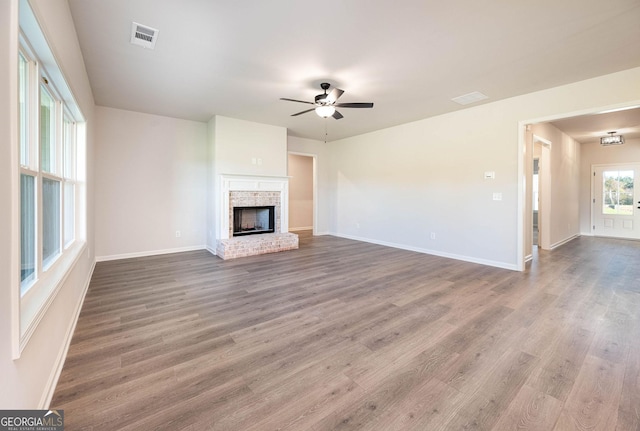 unfurnished living room featuring ceiling fan, a fireplace, and wood-type flooring