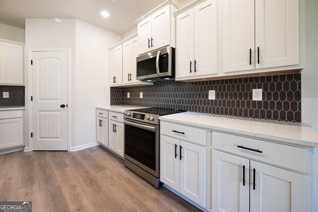 kitchen featuring white cabinets, decorative backsplash, light hardwood / wood-style floors, and stainless steel appliances