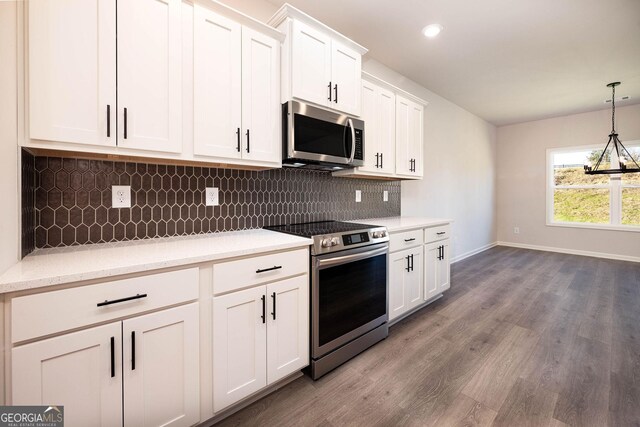 kitchen featuring backsplash, hanging light fixtures, hardwood / wood-style flooring, white cabinetry, and stainless steel appliances