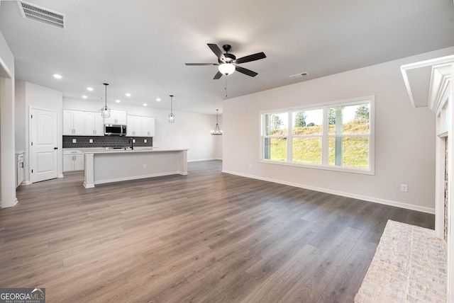 unfurnished living room featuring ceiling fan and dark hardwood / wood-style flooring