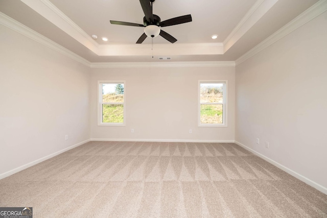 carpeted spare room featuring a tray ceiling, a wealth of natural light, crown molding, and ceiling fan