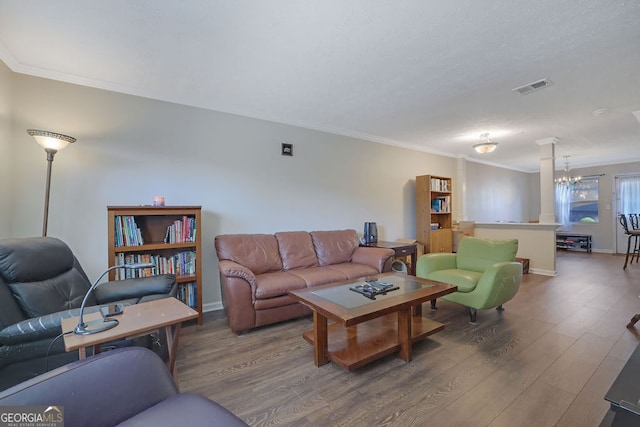 living room featuring an inviting chandelier, wood-type flooring, and ornamental molding