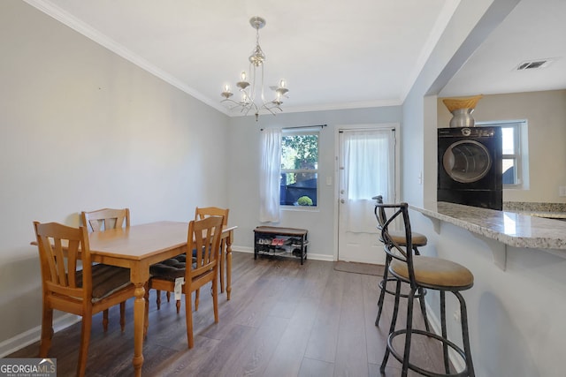 dining room with washer / clothes dryer, an inviting chandelier, crown molding, and dark hardwood / wood-style flooring