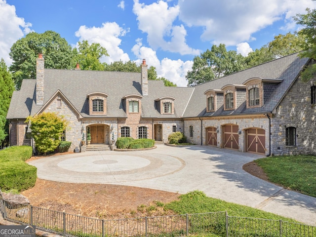 french country home with curved driveway, a chimney, and fence