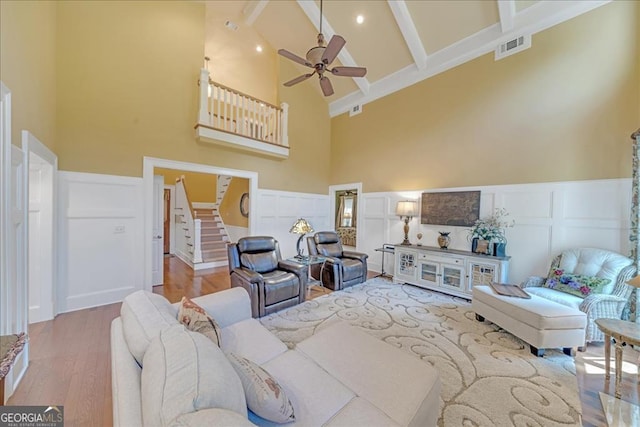 living room featuring high vaulted ceiling, ceiling fan, light wood-type flooring, and beam ceiling