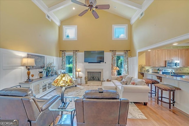 living room with light wood-type flooring, high vaulted ceiling, beamed ceiling, and ceiling fan