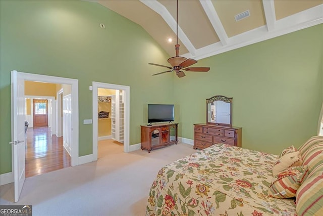 bedroom with light carpet, beamed ceiling, connected bathroom, ceiling fan, and a towering ceiling