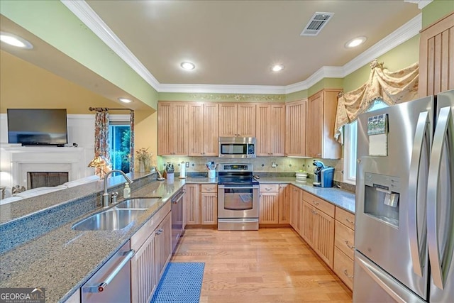 kitchen featuring appliances with stainless steel finishes, light hardwood / wood-style floors, crown molding, and sink