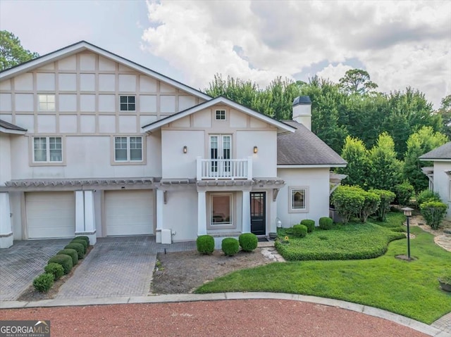 view of front of home featuring a garage, a balcony, and a front yard