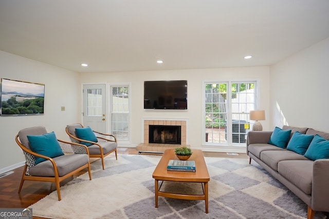 living room with light wood-type flooring and a tiled fireplace