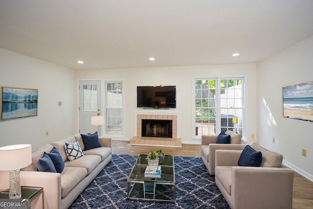 living room with hardwood / wood-style flooring and a tiled fireplace