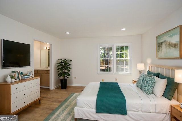 bedroom with sink, ensuite bathroom, and light hardwood / wood-style floors