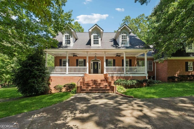 cape cod house with a front lawn, ceiling fan, and covered porch