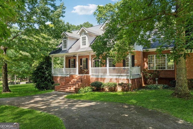 cape cod home with a porch and a front lawn