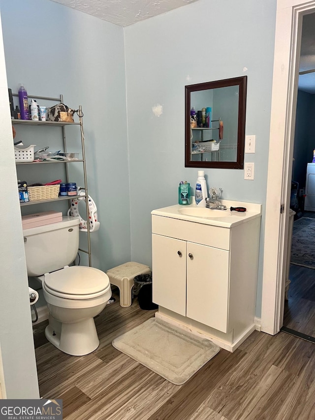 bathroom with toilet, wood finished floors, and vanity