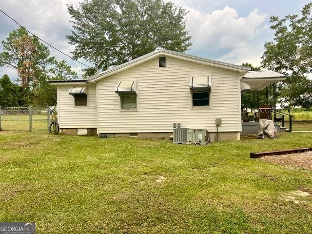 view of side of property featuring central AC, a lawn, and fence