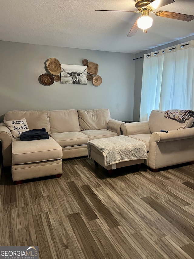 living room with ceiling fan, dark hardwood / wood-style flooring, and a textured ceiling