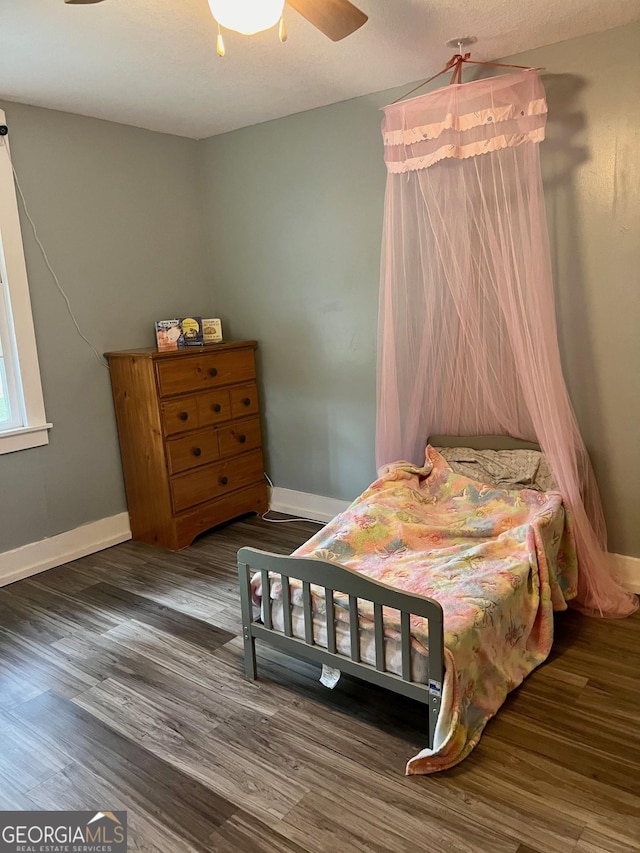 bedroom with a ceiling fan, baseboards, and wood finished floors