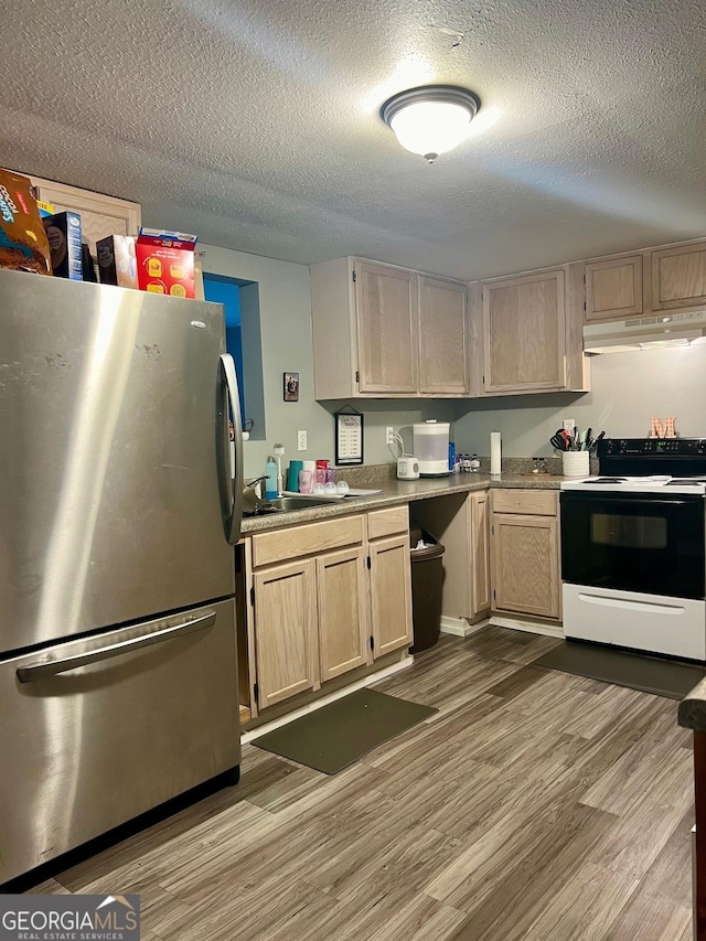 kitchen with light brown cabinets, under cabinet range hood, wood finished floors, freestanding refrigerator, and electric range oven