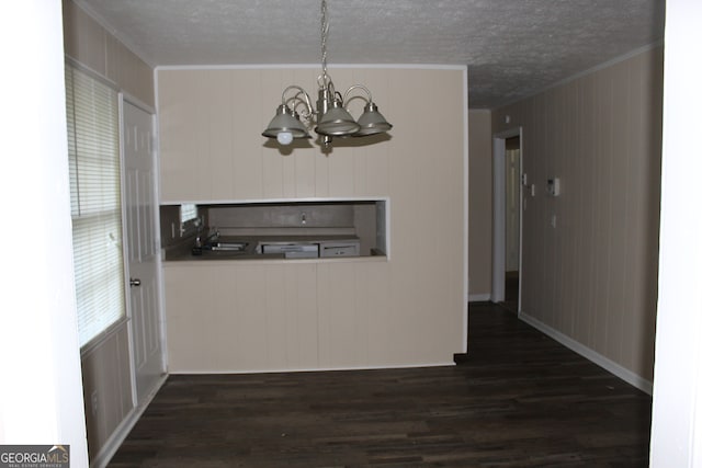 unfurnished dining area with wood walls, dark hardwood / wood-style flooring, a notable chandelier, and ornamental molding