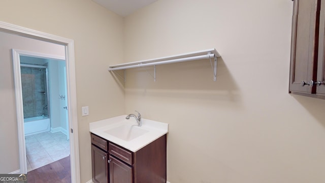 clothes washing area with tile patterned floors, baseboards, and a sink