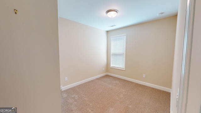 empty room with visible vents, baseboards, and light colored carpet