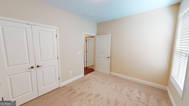 unfurnished bedroom with visible vents, baseboards, carpet, and a closet