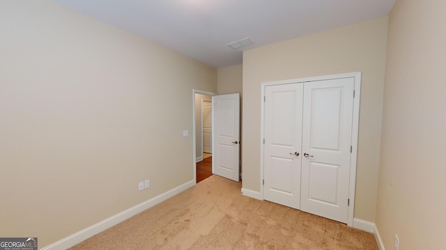 unfurnished bedroom featuring visible vents, baseboards, light colored carpet, and a closet