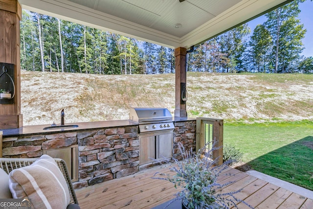 wooden terrace featuring sink, an outdoor kitchen, a lawn, and a grill