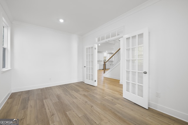 unfurnished room featuring crown molding, light wood-type flooring, and french doors