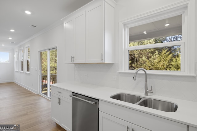 kitchen featuring a wealth of natural light, dishwasher, sink, white cabinets, and ornamental molding