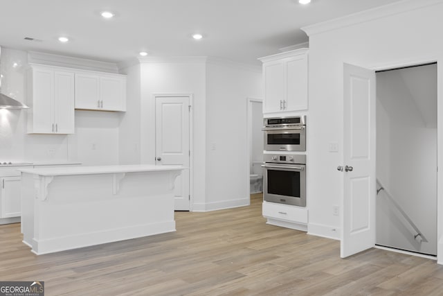 kitchen featuring double oven, white cabinets, a center island, cooktop, and crown molding