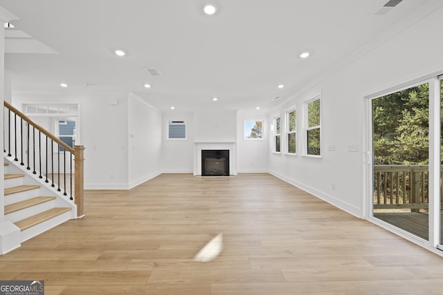 unfurnished living room featuring light hardwood / wood-style flooring and ornamental molding