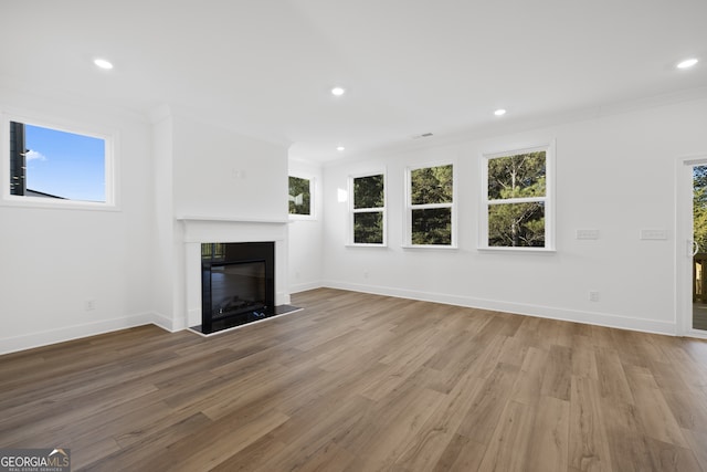 unfurnished living room featuring hardwood / wood-style floors and crown molding