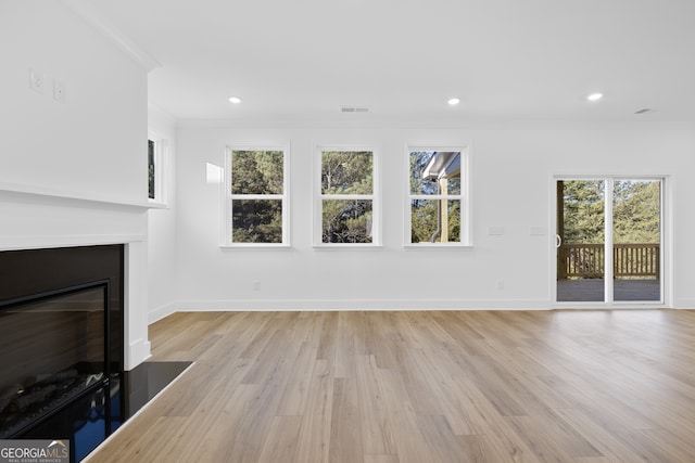 unfurnished living room with ornamental molding and light hardwood / wood-style floors