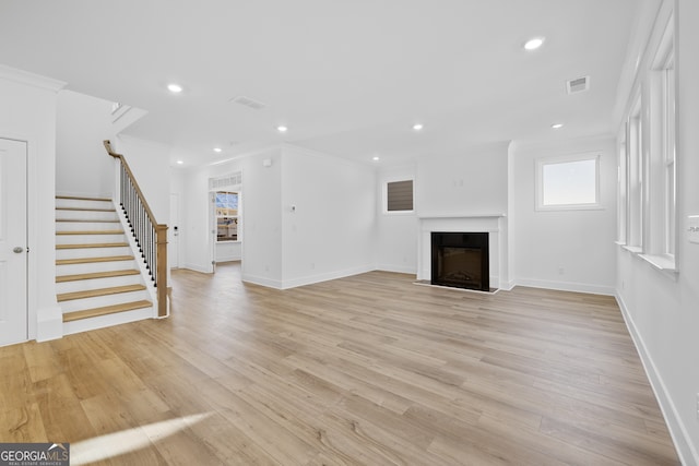 unfurnished living room with light hardwood / wood-style flooring and ornamental molding