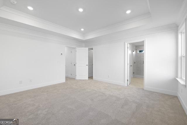 unfurnished bedroom with ensuite bath, ornamental molding, a tray ceiling, and light carpet