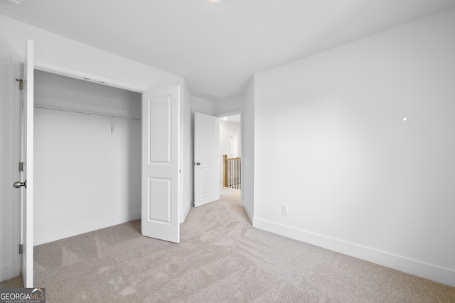 unfurnished bedroom with light colored carpet and a closet