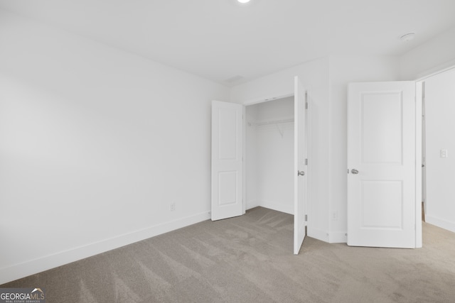 unfurnished bedroom with a closet and light carpet