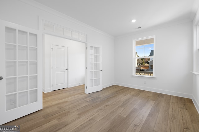 empty room with crown molding, french doors, and light wood-type flooring